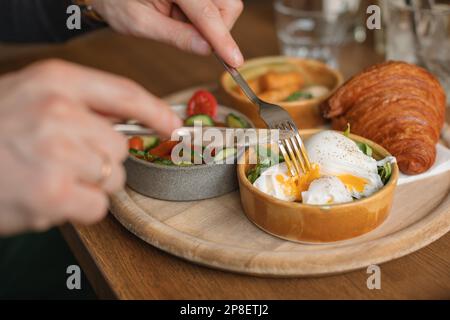 Primo piano di una persona che mangia uova in camicia a colazione Foto Stock