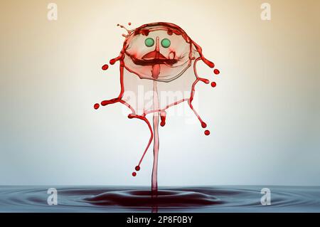 Primo piano di una goccia d'acqua e corona di spruzzi con un volto sorridente Foto Stock