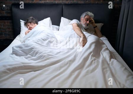 Coppia anziana che dormiva in albergo, uomo che guardava la macchina fotografica Foto Stock