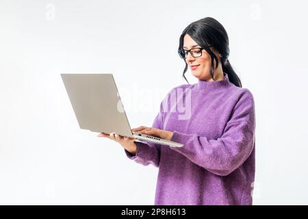 Una giovane donna caucasica che indossa occhiali e digita sul suo laptop su uno sfondo bianco. Foto Stock