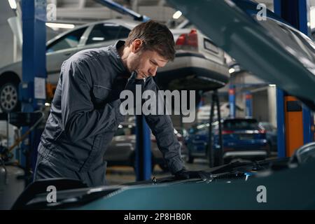 Il maschio esegue un controllo tecnico completo della macchina Foto Stock