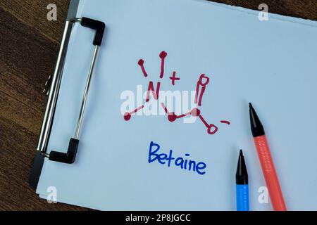 Concetto di molecola di betaina scrivere su carta, formula chimica strutturale isolato su tavola di legno. Foto Stock