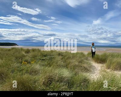 Findhorn, Moray, Scozia - 7 agosto 2022: Donna sola colorata sulla spiaggia di Findhorn, Moray costa, Scozia. Giornata di sole sulla spiaggia di Findhorn. Foto Stock