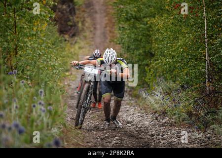 due ciclisti salgono con la loro mountain bike. salita pesante su pendenze fangose. gara ciclistica di fondo Foto Stock