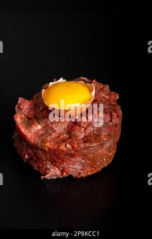 Tartare di bistecca su ardesia nera con un uovo Foto Stock