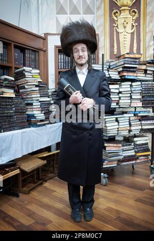 Ritratto di un ebreo ortodosso che indossa una streimella e tiene una megillah, in una sinagoga di New York City. Foto Stock