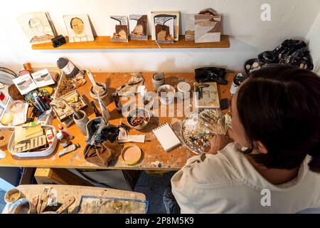 Un'artista femminile è seduta alla sua scrivania, diligentemente lavorando sul suo ultimo capolavoro creativo Foto Stock