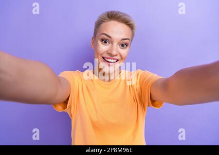 Primo piano selfie ritratto cadre di eccitato divertente popolare blogger sorridente godere la sua nuova stomatologia veneers bianco isolato su sfondo di colore viola Foto Stock