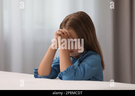 Ragazza cute che dice la preghiera di bedtime a casa Foto Stock