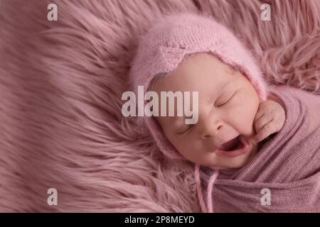 Adorabile neonato sdraiato su pelliccia sintetica, vista dall'alto. Spazio per il testo Foto Stock