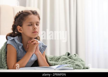 Ragazza carina che prega sopra la Bibbia in camera da letto Foto Stock