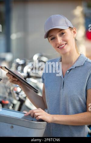 bella lavoratrice che ripara le biciclette all'aperto Foto Stock