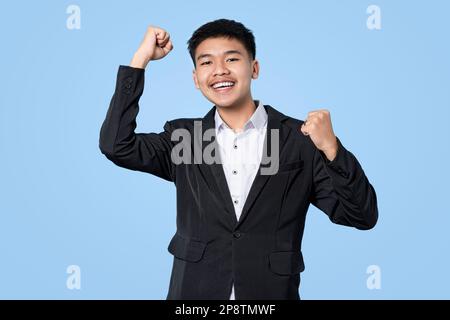 Giovane bell'uomo d'affari asiatico eccitato celebrare il successo isolato su sfondo di luce blu Foto Stock