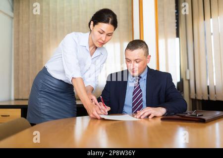 Documenti per la firma di uomini d'affari portati dalla partner femminile nella sala riunioni Foto Stock