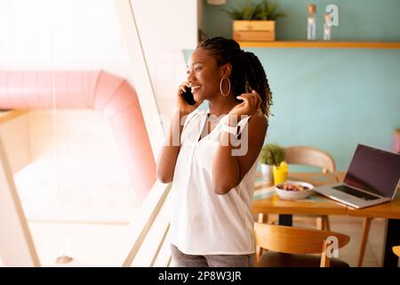 Giovane donna nera che usa il telefono cellulare nel bar Foto Stock