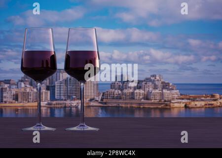 Bicchiere di due vini rossi con vista sul porto di Sliema e sui grattacieli di Malta. Vista da la Valletta. Foto Stock