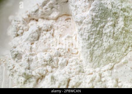 l'acqua è aggiunta alla farina. Impastare l'impasto per la cottura. Primo piano. La farina e l'acqua sono mescolati Foto Stock