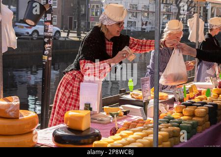 Venditori di formaggio femminile con abbigliamento tradizionale in una bancarella del mercato del formaggio Alkmaar nei Paesi Bassi. Foto Stock