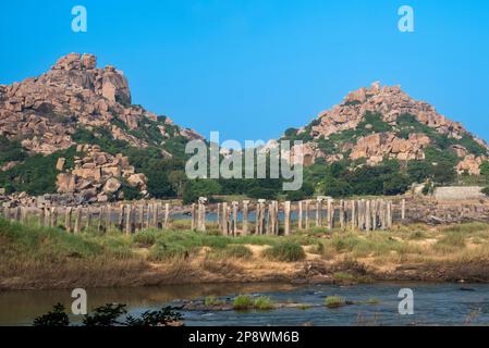 Colonne di pietra del vecchio ponte abbandonato del fiume Tungabhadra, Hampi, India. Hampi, la capitale dell'Impero Vijayanagara, è patrimonio dell'umanità dell'UNESCO Foto Stock