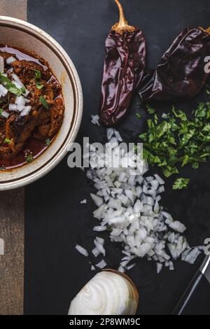 Una ciotola di carne di birria cotta lentamente e brasata in una ciotola d'annata con cipolle tritate, coriandolo, peperoni guajillo e brodo Foto Stock