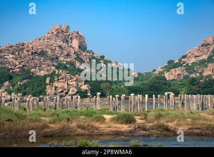 Colonne di pietra del vecchio ponte abbandonato del fiume Tungabhadra, Hampi, India. Hampi, la capitale dell'Impero Vijayanagara, è patrimonio dell'umanità dell'UNESCO Foto Stock