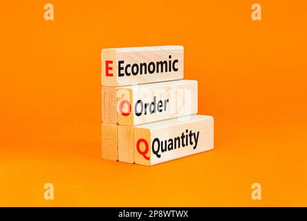 Simbolo quantità ordine economico EOQ. Concetto parole EOQ ordine economico quantità su blocchi di legno su una bella tavola arancione sfondo arancione. Business Foto Stock