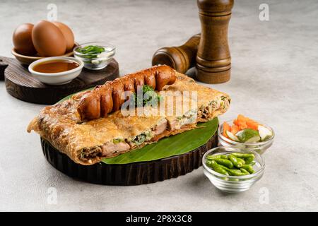 Martabak telur è cibo di strada indonesiano, fatto con saporita pasta fritta in padella farcita con uova, cipollina, carne, salsiccia, spezie e formaggio. Foto Stock