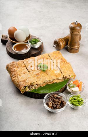 Martabak telur è cibo di strada indonesiano, fatto con saporita pasta fritta in padella farcita con uova, cipollina, carne, salsiccia, spezie e formaggio. Foto Stock