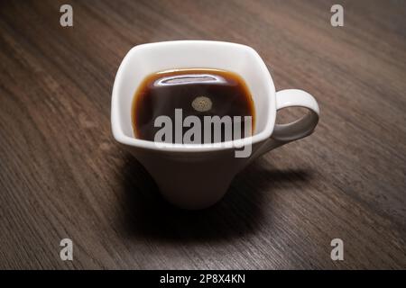 Tazza quadrata bianca con caffè nero caldo su tavolo di legno Foto Stock