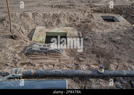 terreno edificabile in sabbia con due pozzi di cemento e tubi di plastica Foto Stock