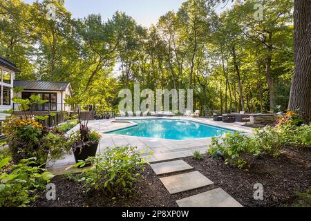 Una grande piscina e' circondata da una piscina in un lussureggiante cortile verde Foto Stock
