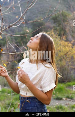 Una giovane donna elegante nella natura che guarda verso gli alberi offre un momento di pace Foto Stock