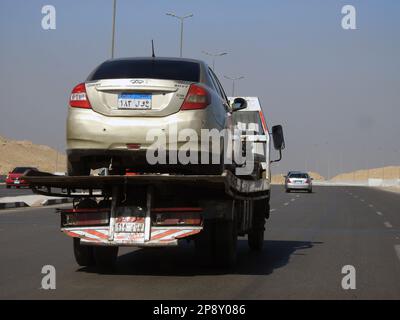 Cairo, Egitto, 8 2023 marzo: Un carro attrezzi per il recupero del rimorchio autocarro idraulico a pianale che sposta un'auto rotta che si muove per strada, fuoco selettivo di recupero Foto Stock