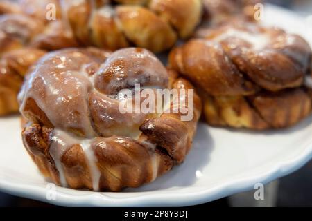 Ciambelle di cannella con glassa bianca su un piatto bianco Foto Stock