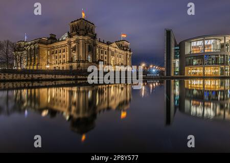 Vista degli edifici governativi di notte. Reichstag a Berlino all'ora blu. Edifici storici illuminati. Fiume Sprea con riflessione sull'acqua Foto Stock