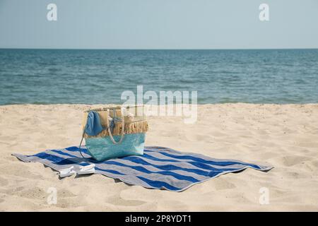 Telo da spiaggia con borsa, infradito e costume da bagno sulla sabbia Foto Stock