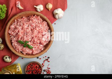 Carne di pollo crudo macinata e ingredienti su tavola grigia, piatto. Spazio per il testo Foto Stock