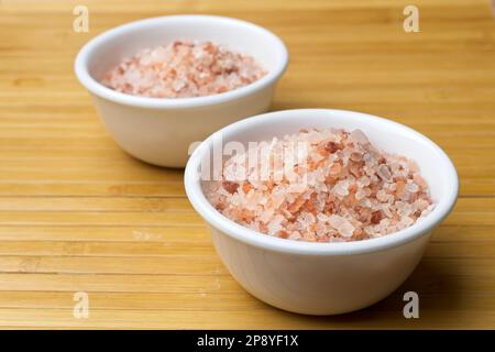 Un primo piano studio foto di sale marino rosa Himalayano culo in piccole ciotole bianche. Foto Stock
