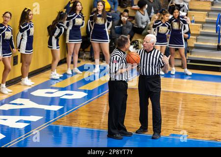 Due funzionari IHSAA conferiscono al tribunale di fronte al cheerleaders Hammond Noll durante una partita nella palestra North Judson - San Pierre High School. Foto Stock