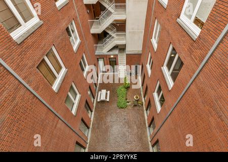 un edificio di appartamenti con pareti in mattoni e scale che conducono al secondo piano, guardando verso il basso dal livello superiore Foto Stock