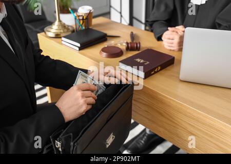 Uomo che prende la tangente dalla valigetta per giudice in aula, primo piano Foto Stock
