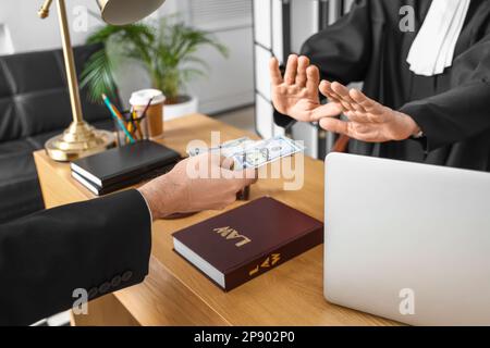 Giudice maturo che rifiuta di prendere la tangente dall'uomo in tribunale, primo piano Foto Stock
