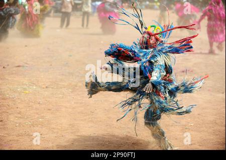 Una maschera colorata in fibra che esegue una danza frenetica al Festival di stima a Dedougou, Burkina Faso Foto Stock