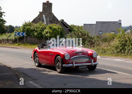 Kerlaz, Francia - Luglio 17 2022: Coppia in pensione in crociera in una rossa Austin-Healey 3000 Mark III BJ8 sport convertibile. Foto Stock