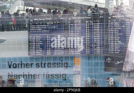 10 marzo 2023, Baviera, München-Flughafen: I passeggeri si accodano dietro il display per raggiungere il controllo di sicurezza. All'aeroporto di Monaco, i dipendenti che hanno controllato il bagaglio a mano e il bagaglio sono andati in sciopero questa mattina. Foto: Peter Kneffel/dpa Foto Stock