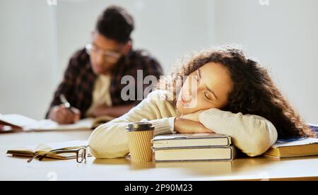 Studiare può essere estenuante. Scatto corto di una giovane studentessa attraente dell'università che dorme sui suoi libri di testo in classe. Foto Stock