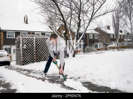 Un uomo libera la neve dalla sua guida a Leeds. Data immagine: Venerdì 10 marzo 2023. Foto Stock