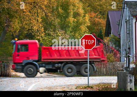 Un grande camion rosso di consegna che passa oltre un segnale di stop Foto Stock