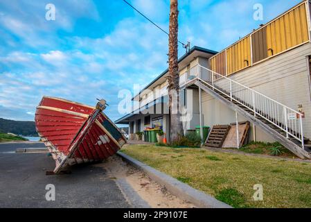 Una barca di legno costruita da clinker aperta siede alta e asciutta su una strada accanto al noleggio di Andersons Boat a Ettalong Beach sulla costa centrale del New South Wales Foto Stock