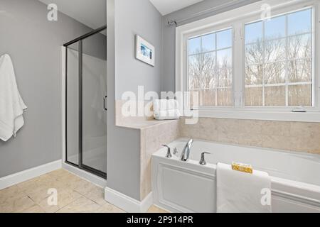 Un bagno pulito con doccia, vasca e grande finestra Foto Stock